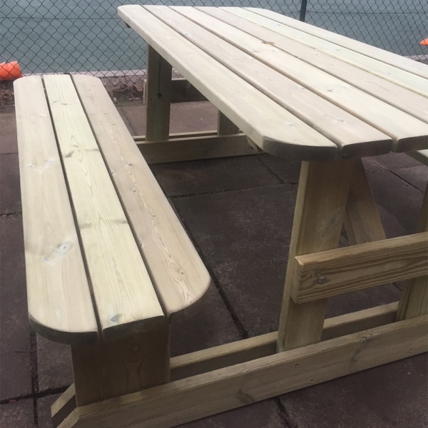 Wooden picnic bench with rounded edges and H-frame design at a sports club