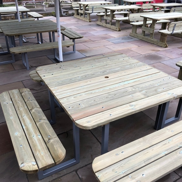 Multiple traditional pub style picnic benches for 12 people with steel frames and rounded edges in a beer garden