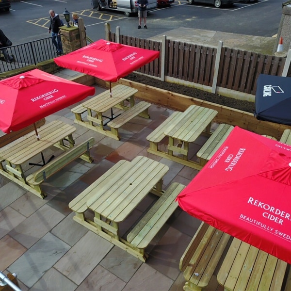 Multiple traditional pub-style picnic benches with rounded edges in outdoor bar area