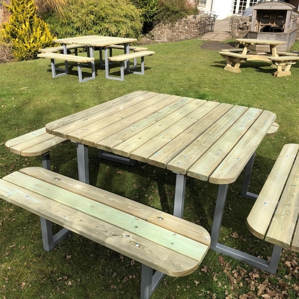 Multiple large 12 seater wooden picnic tables with rounded edges and steel frames